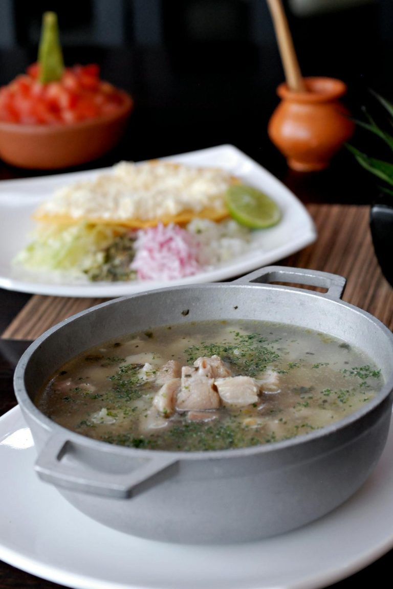 Savory Mexican pozole soup served in a traditional pot with lime, highlighting authentic flavors.
